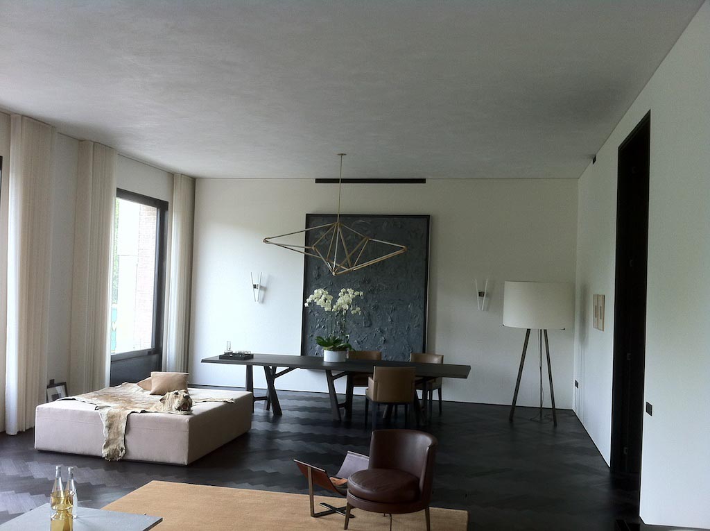 picture of a room with brown sofas and a wooden long table and white suede walls