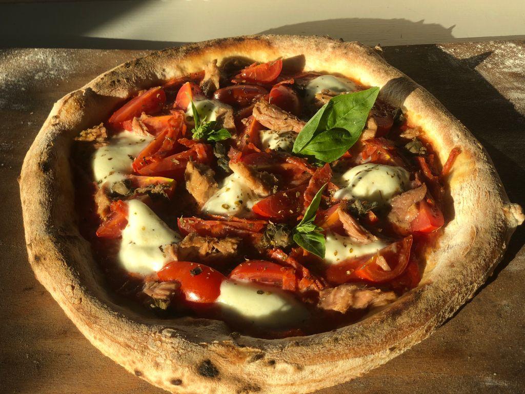 Una pizza con pomodori, mozzarella e basilico sopra
