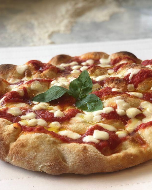 Pizza Margherita con salsa di pomodoro, formaggio fuso e basilico su un piatto bianco