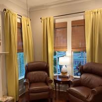 Cozy living room with two brown recliners, yellow curtains, and a table lamp by the window