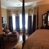 Elegant bedroom with four-poster bed, bay windows, and beige decor