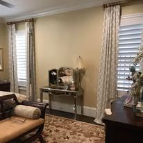 Living room with sofa, console table, patterned rug, and windows with white blinds and curtains