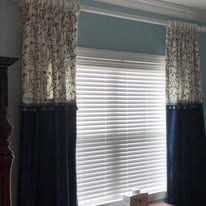 Window with white blinds and navy-and-floral curtains in a light blue room