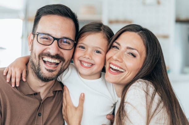 A man and woman are holding a little girl and smiling for the camera.