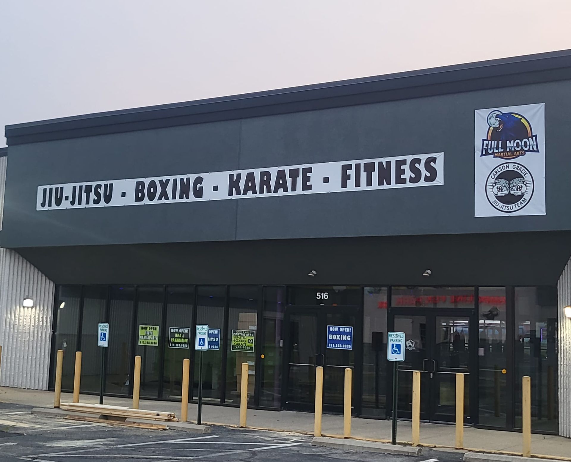 MMA gym storefront with sign reading “JIU-JITSU - BOXING - KARATE - FITNESS” and glass entrance.