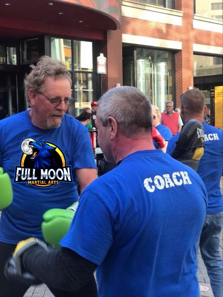 Two men boxing outdoors; one in blue 
