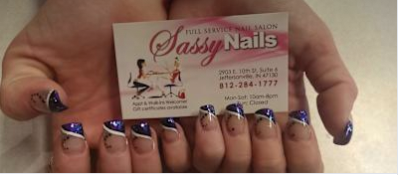Hand with long purple and silver nail art holding a Sassy Nails business card