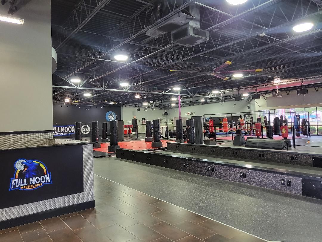 Interior of a gym with punching bags and a reception desk. The gym is branded with the 