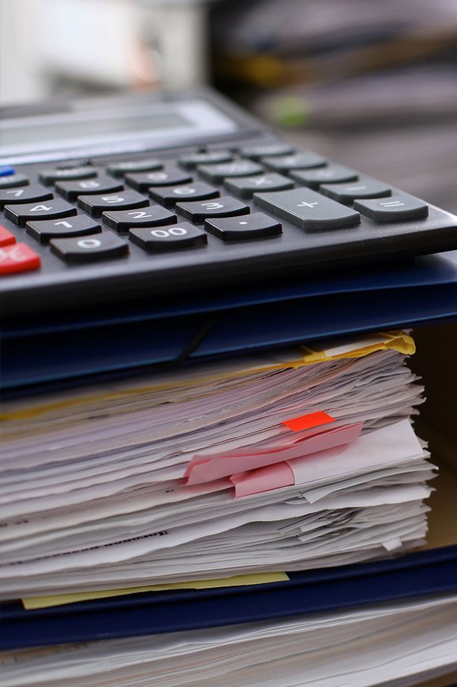 Calculator on top of a stack of papers with colored tabs.