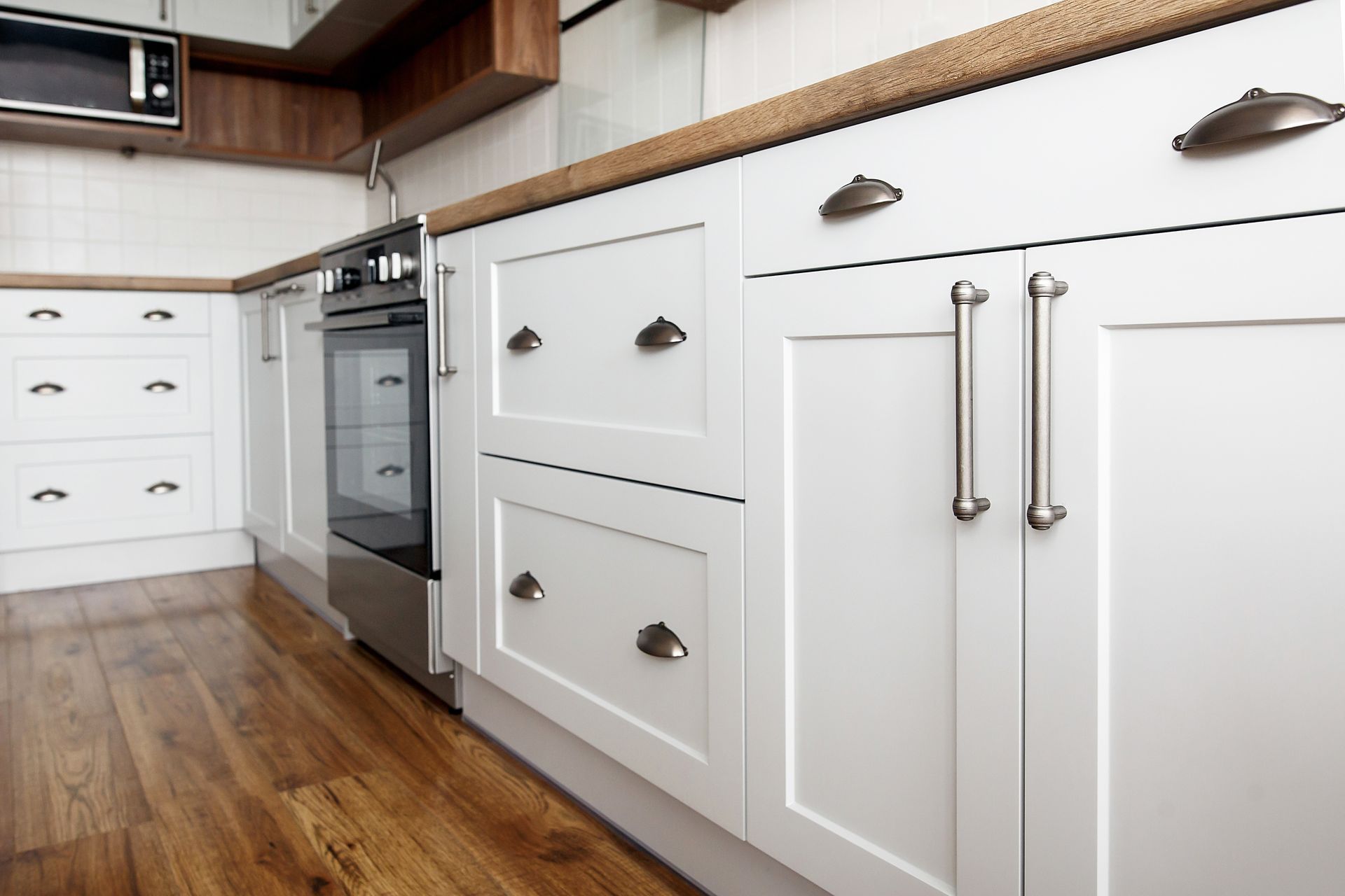 Cuisine équipée d'armoires blanches, de comptoirs en bois, d'un four et d'un plancher en bois franc.