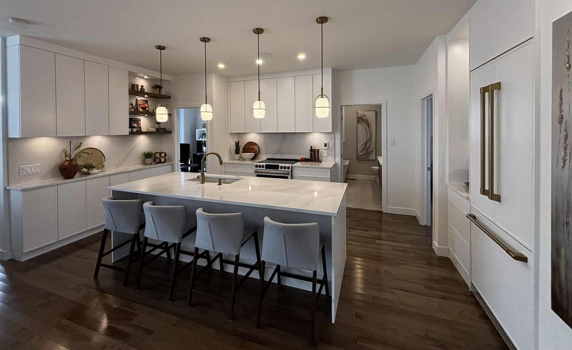 Cuisine blanche moderne avec îlot central, luminaires suspendus et parquet.