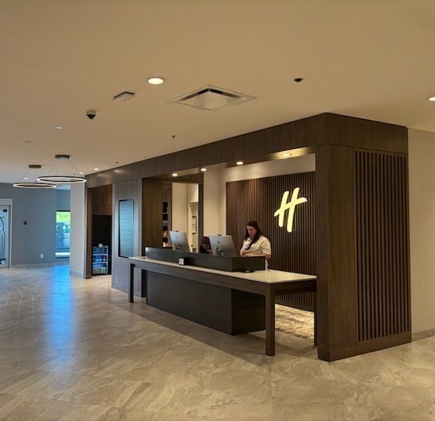 Hall d'hôtel avec réception, un réceptionniste et le logo Holiday Inn.