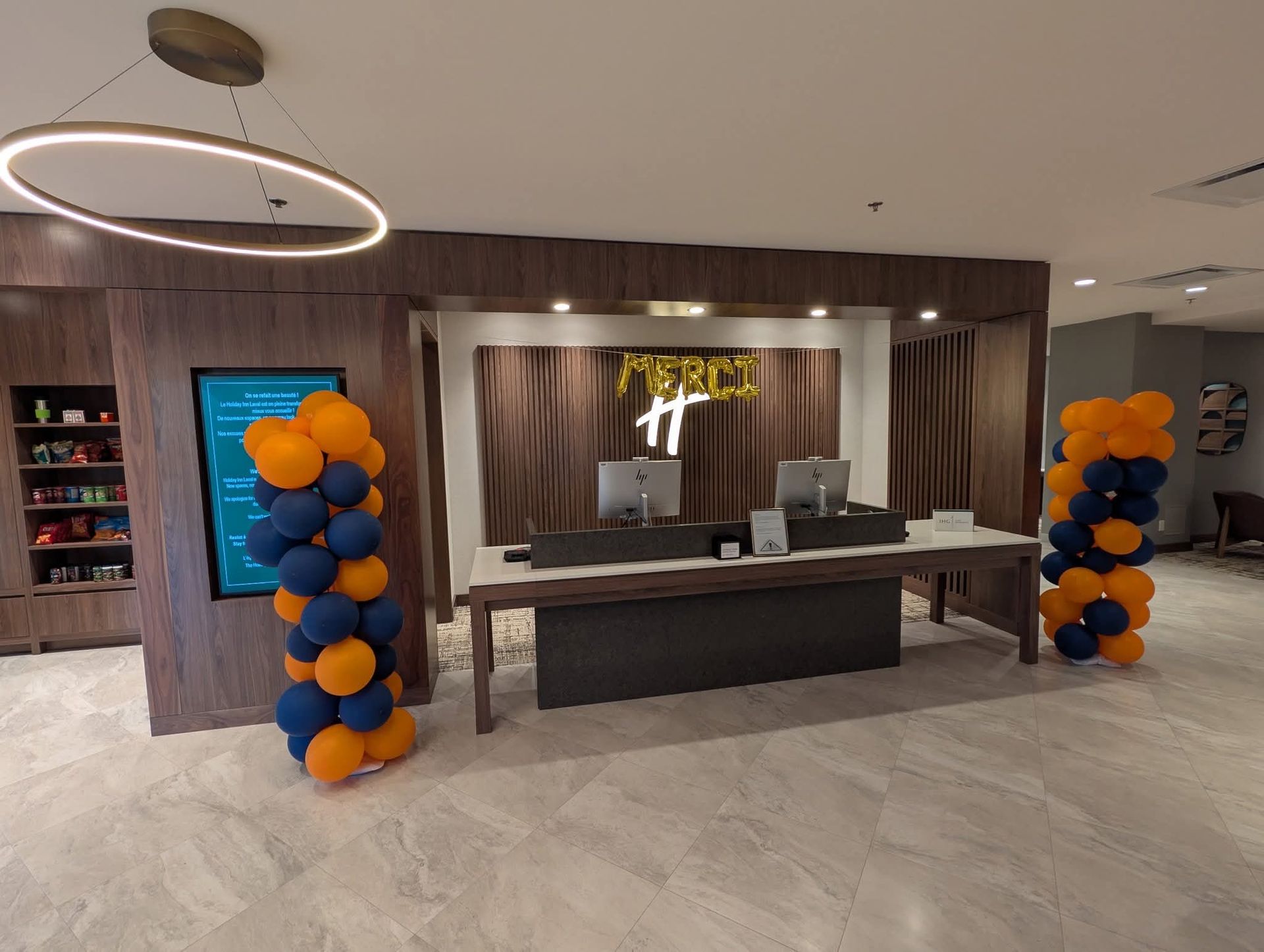 Hall d'entrée avec une réception, des colonnes de ballons et un écran d'affichage, probablement pour un hôtel ou un établissement similaire.