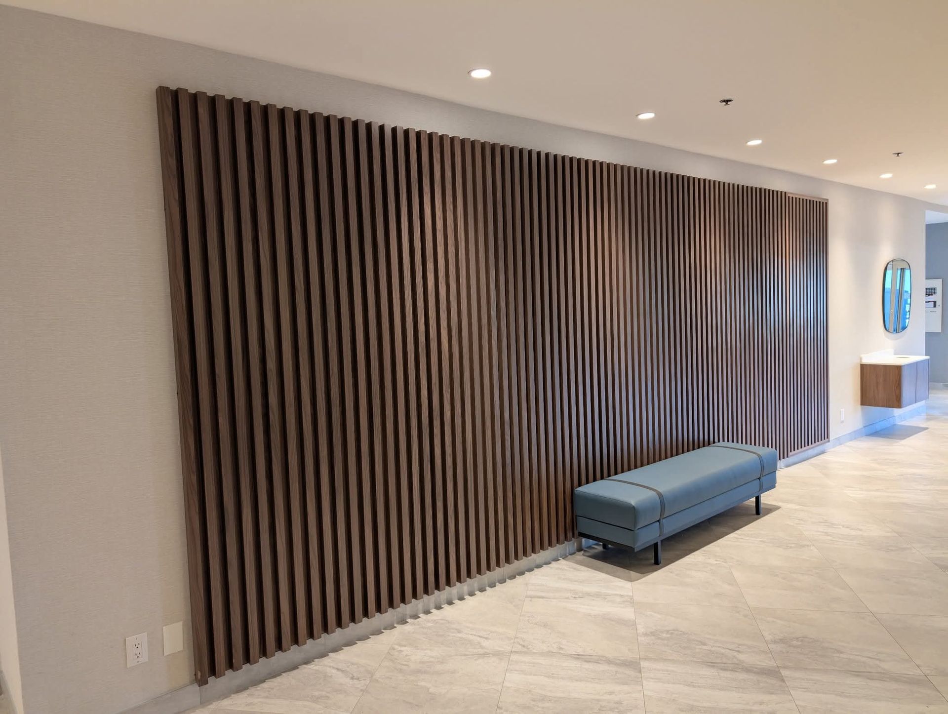 Mur à claire-voie en bois avec un banc bleu devant, dans un intérieur moderne.