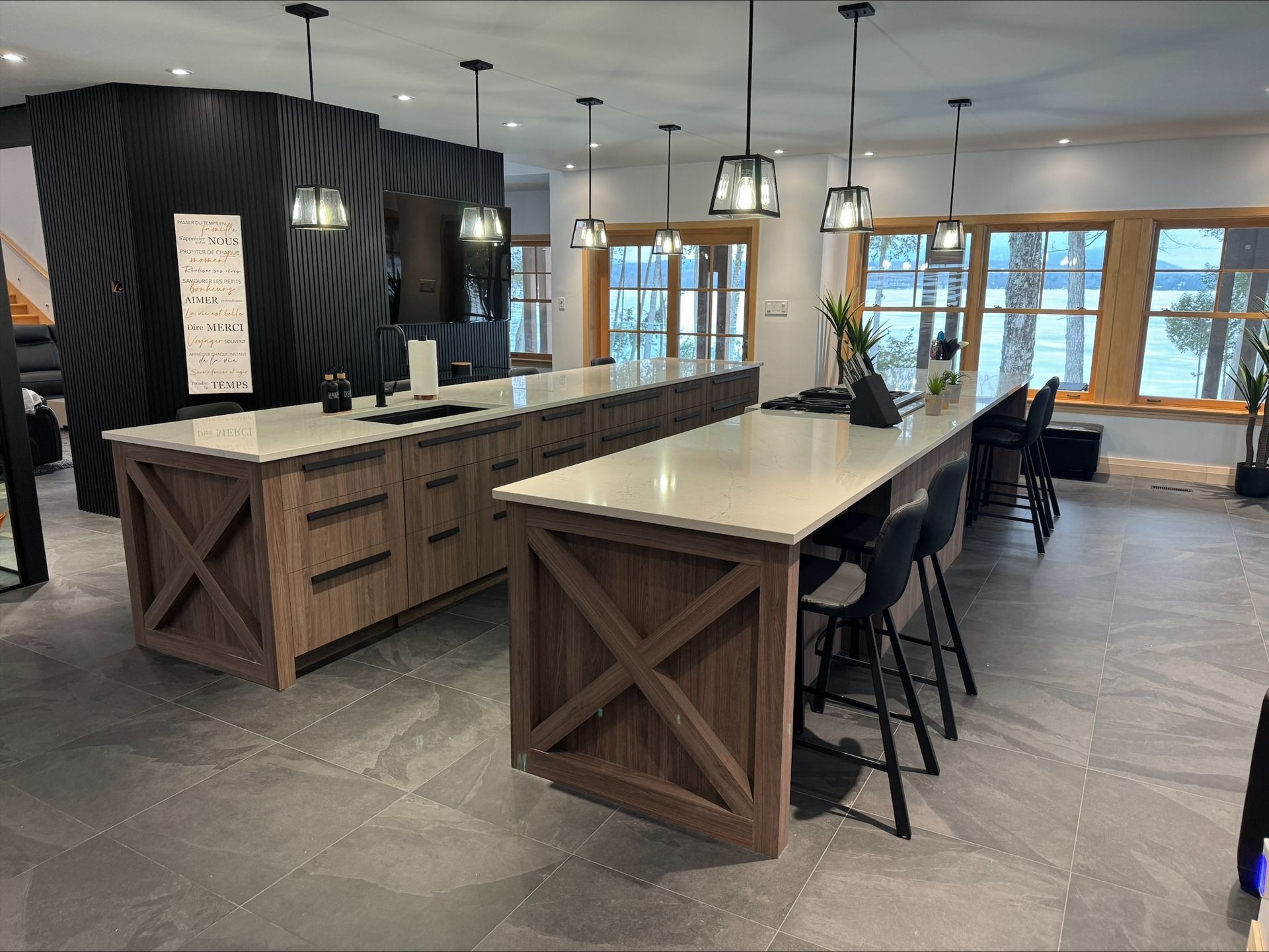 Deux îlots de cuisine avec plans de travail clairs et placards en bois foncé. Luminaires suspendus.