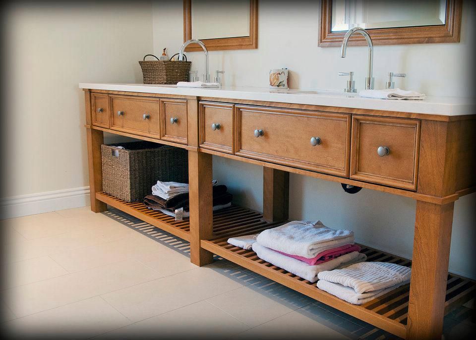 Meuble-lavabo double en bois pour salle de bain avec comptoir en marbre, tiroirs et étagères ouvertes pour ranger les serviettes et les paniers.