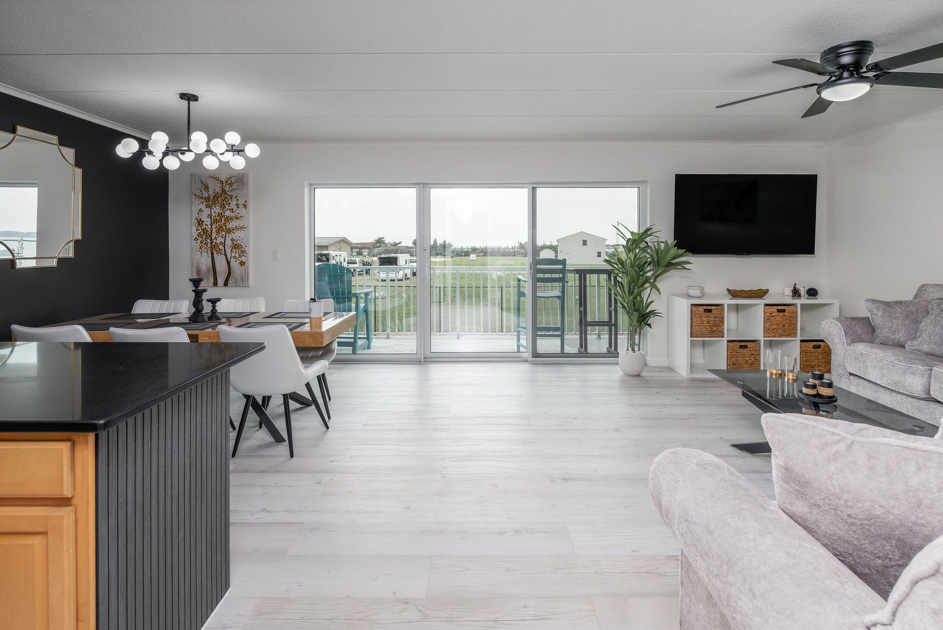 Spacious living room with white walls, sliding glass doors to a balcony, and light wood flooring.
