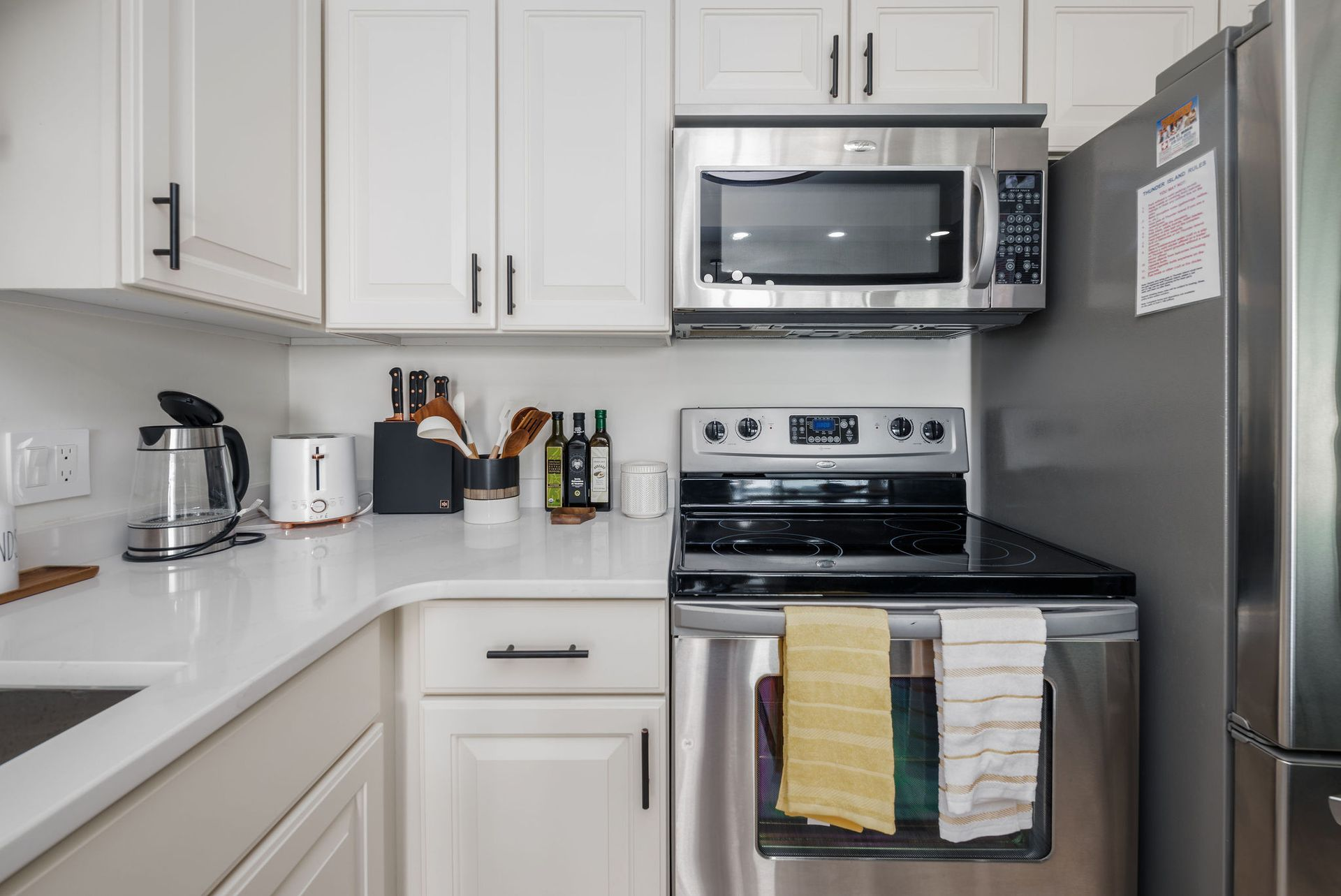 White kitchen with stainless steel appliances, countertops, and cabinets.