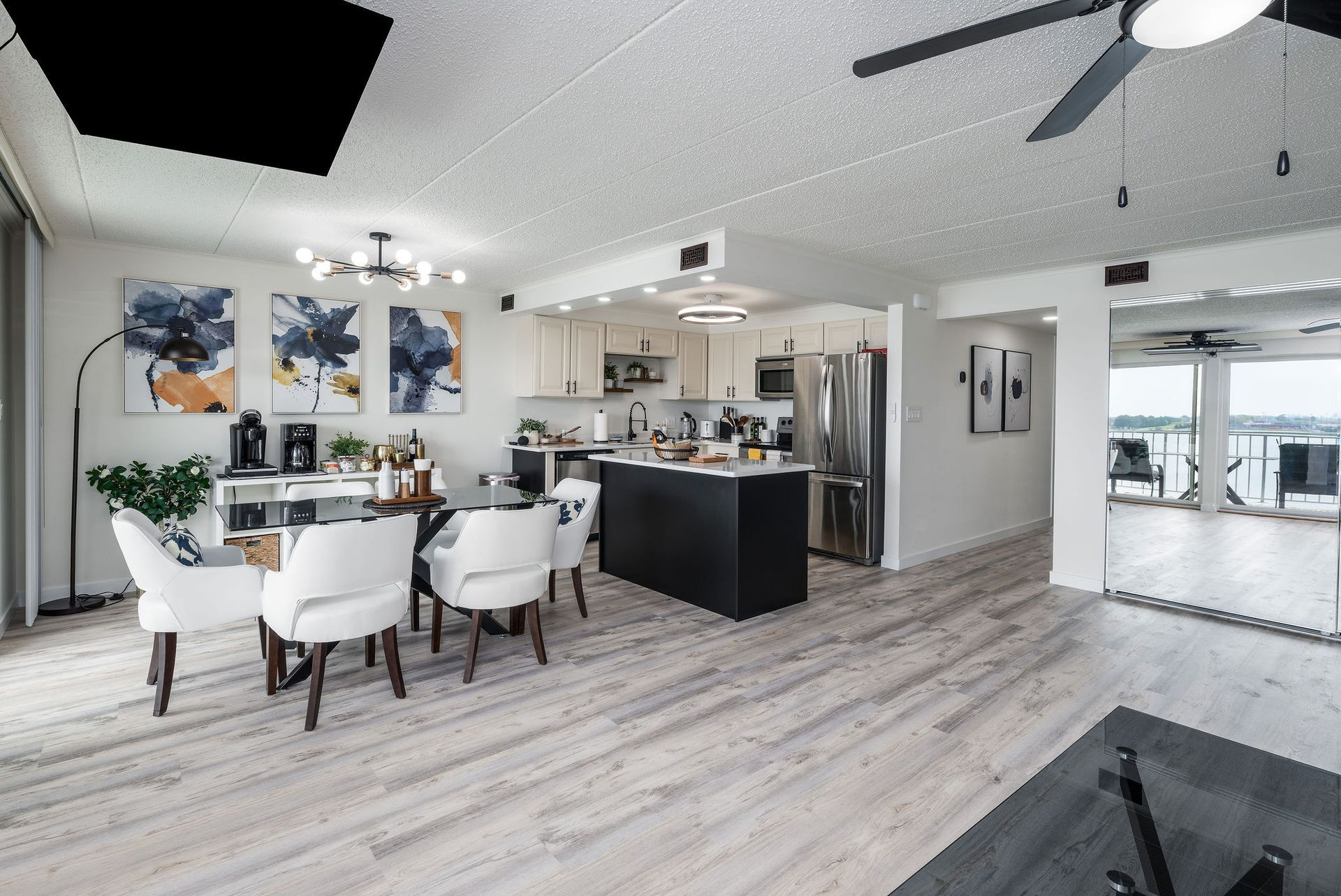 Bright, open-concept condo interior with dining area, kitchen island, and water view.