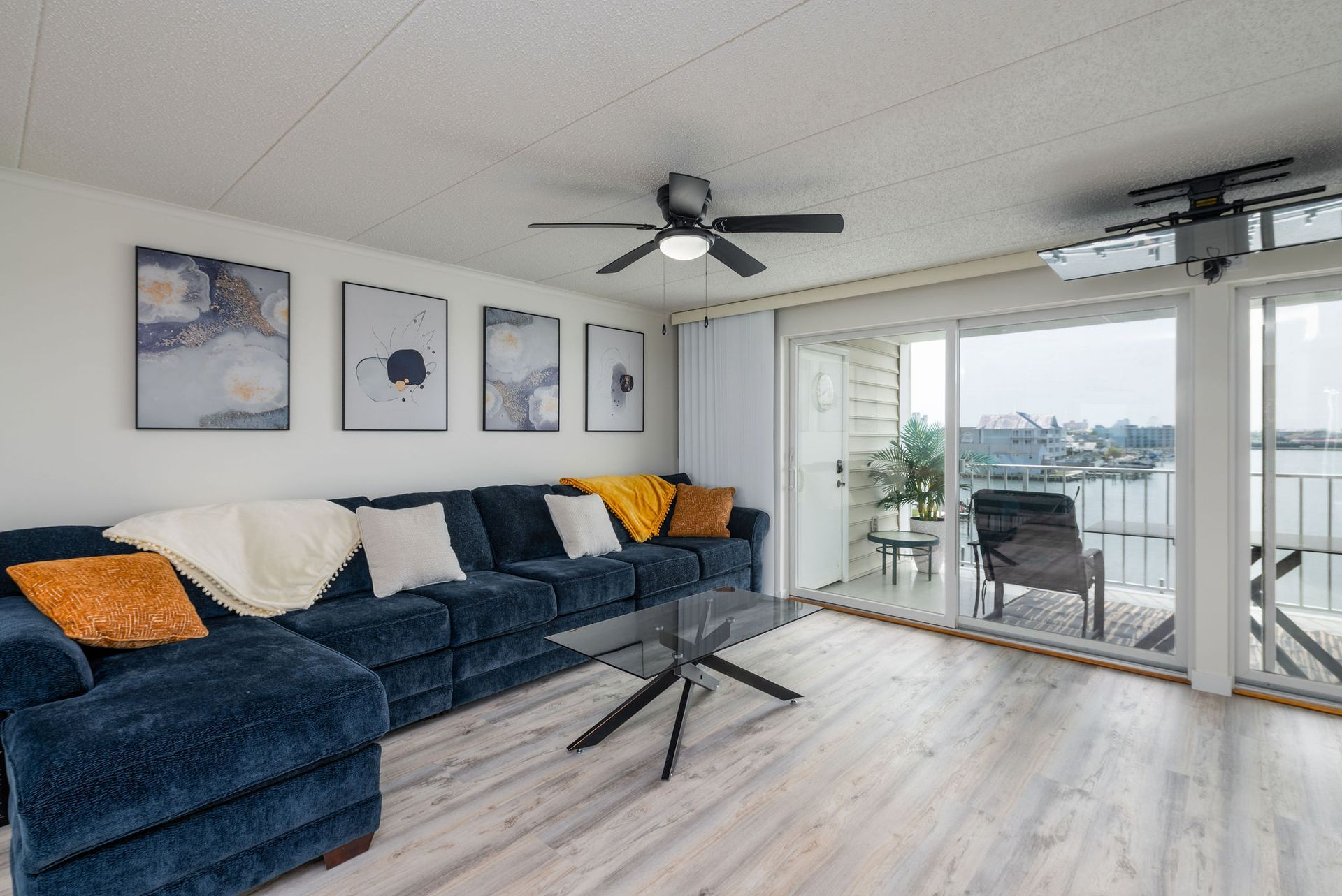 Blue sectional sofa in a bright living room with large windows overlooking a waterfront.
