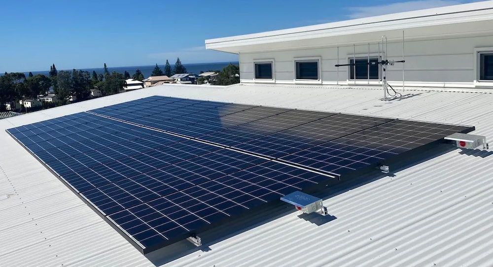 Solar Panels Installed On A White Building Rooftop — Mackies in Port Macquarie, NSW