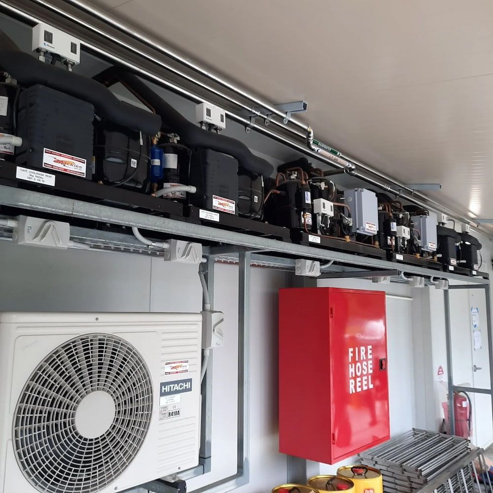 A Fire Hose Reel Is Hanging On A Wall Next To An Air Conditioner — Mackies In Taree, NSW