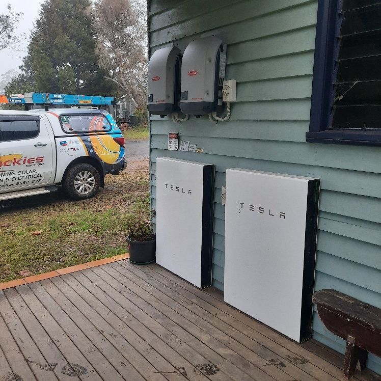 Two White Tesla Powerwall Batteries And Solar Inverters Mounted On A House — Mackies in Taree, NSW