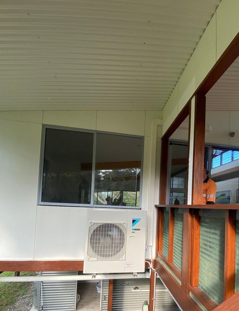 An Air Conditioning Unit Is Installed Below A Window On A Porch — Mackies in Taree, NSW