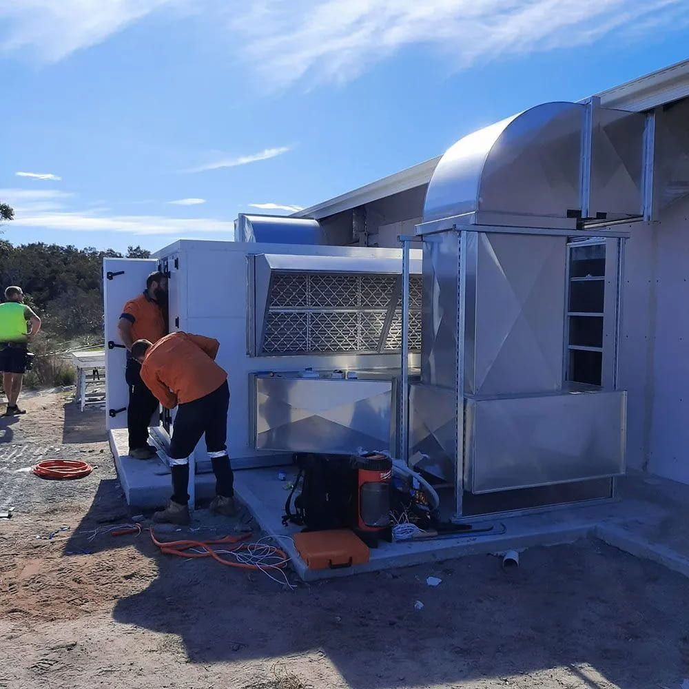 A Group Of Men Are Working On A Machine Outside Of A Building — Mackies In Taree, NSW