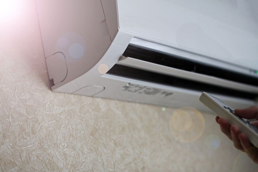 A Person Is Using A Remote Control To Turn On An Air Conditioner — Mackies In Bonny Hills, NSW