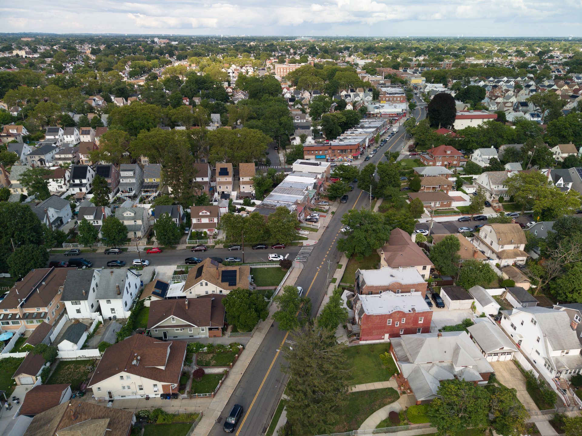 Aerial view of a suburban neighborhood with tree-lined streets and houses stretching toward the horizon