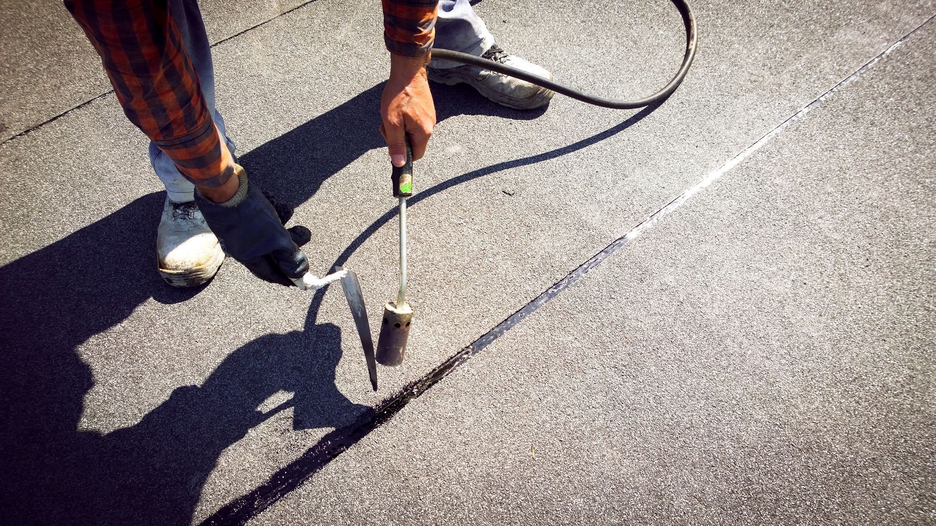 Person using a cane on a sunlit pavement, with a long shadow cast on the ground.