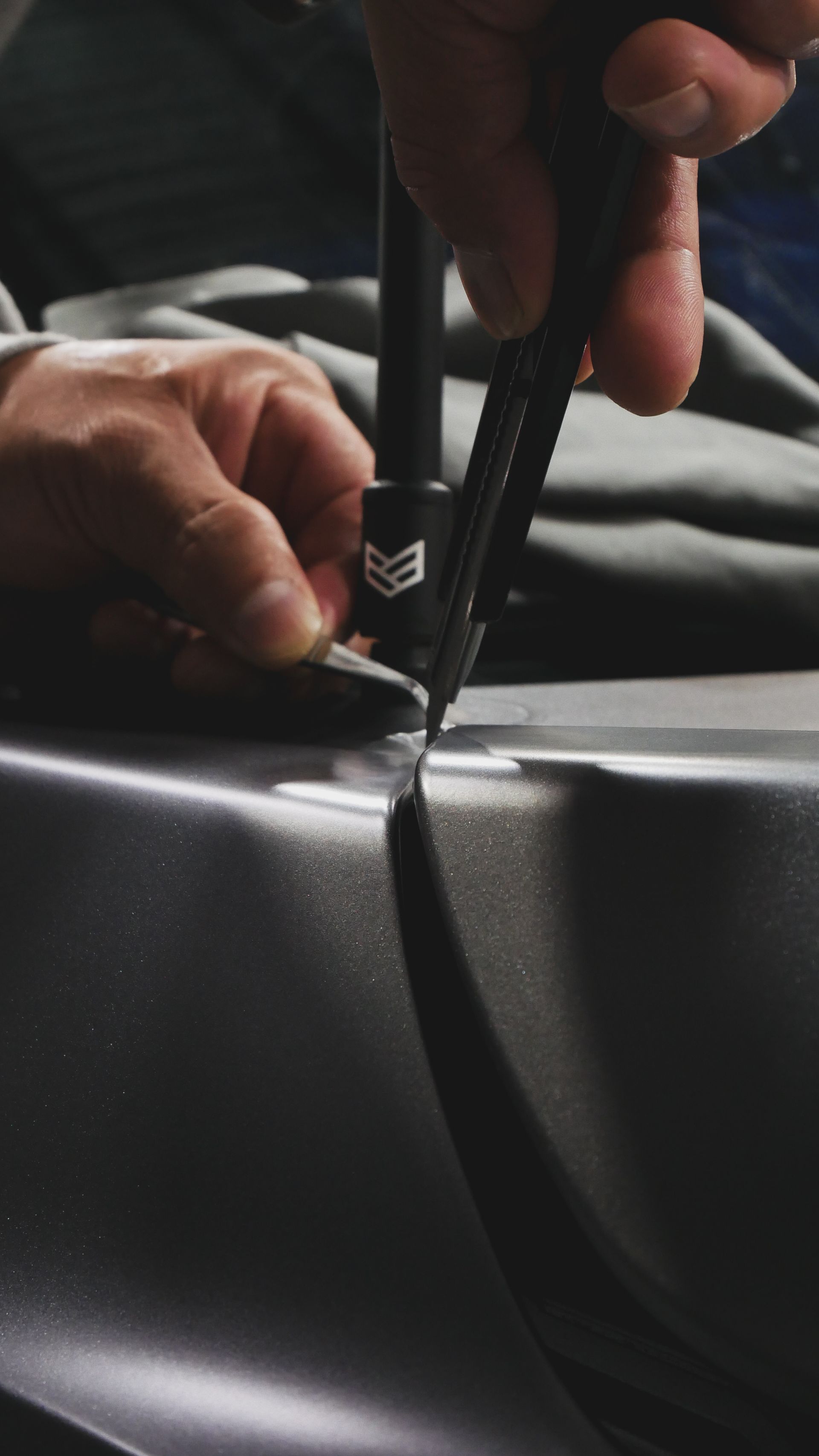 Hands using a seam roller to press black vinyl material