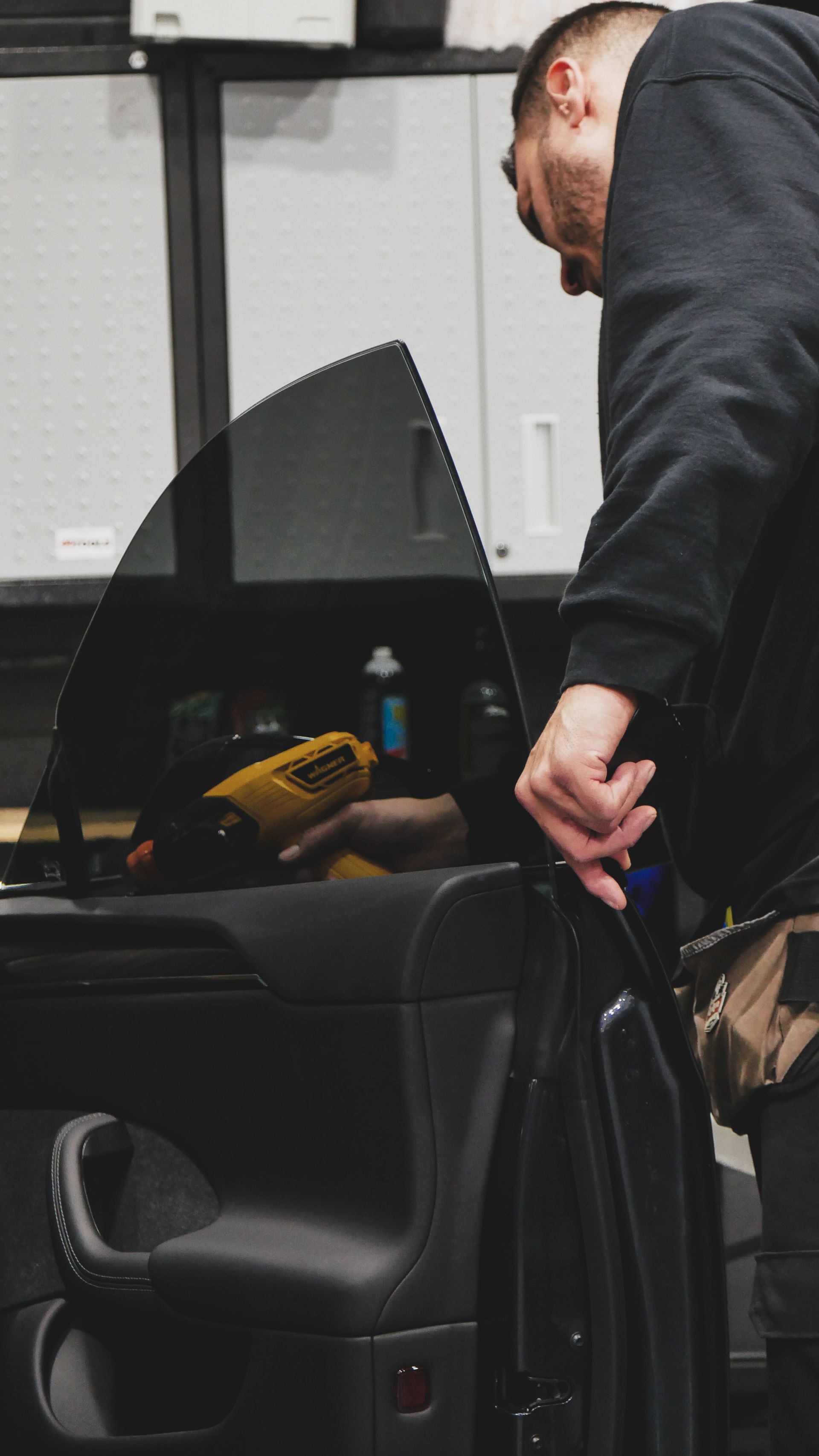 Man standing beside an open car door, leaning into the vehicle in a parking area