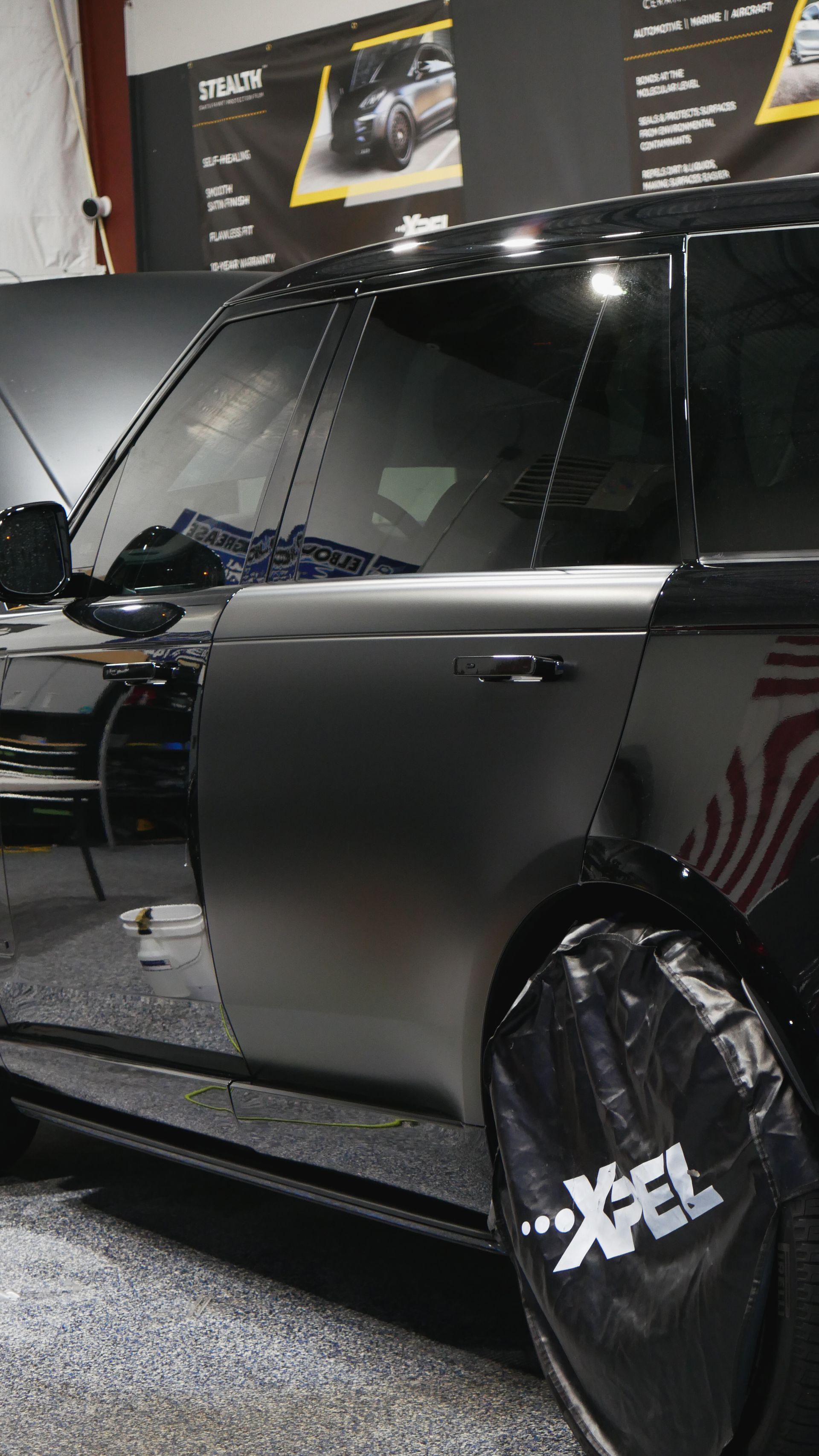 Black SUV with glossy dark paint and large wheels on display at an indoor auto show
