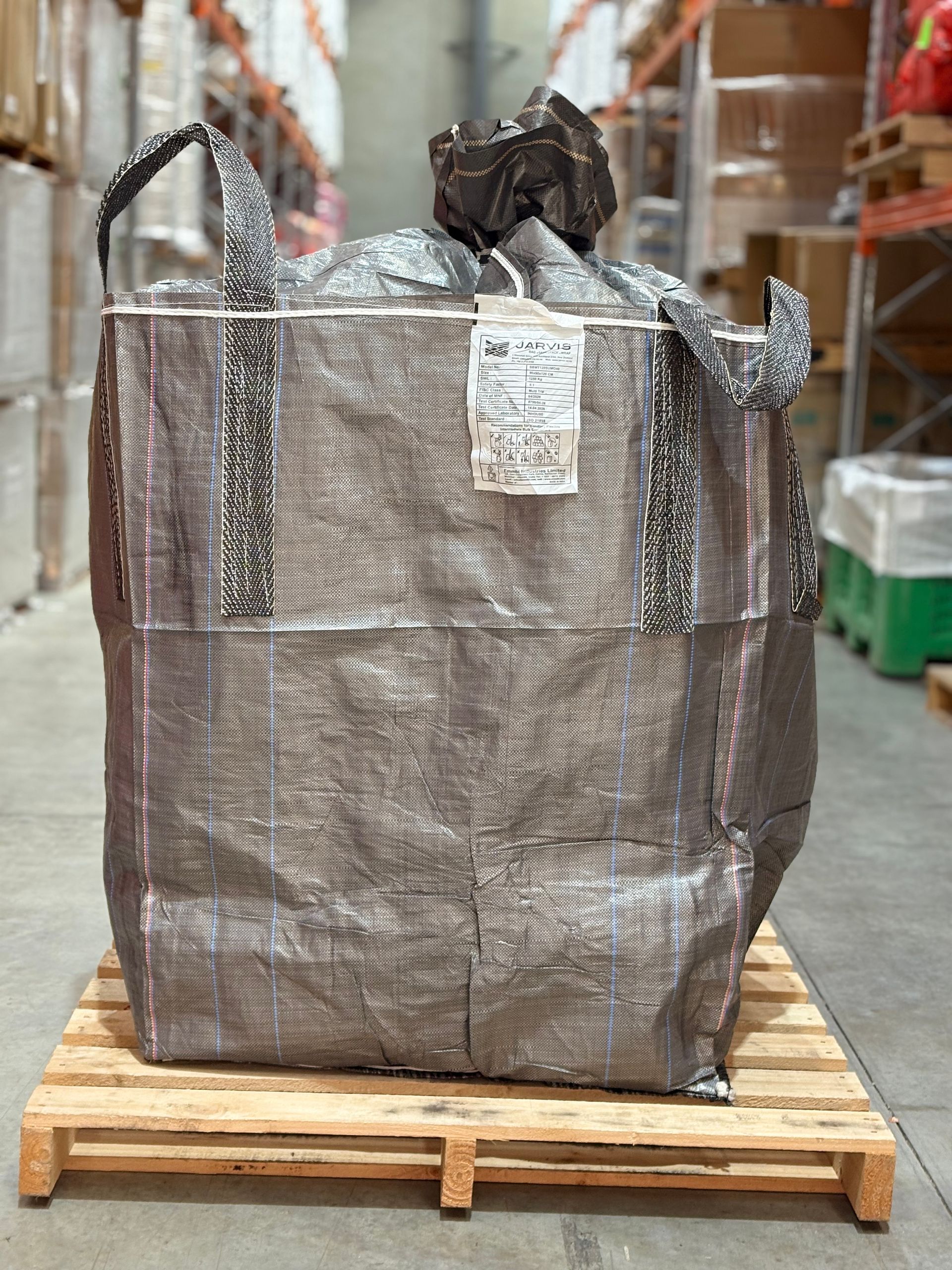 Large silver industrial bulk bag on a wooden pallet in a warehouse aisle