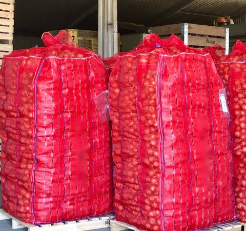 Pallets stacked with large red mesh sacks in a warehouse or storage area