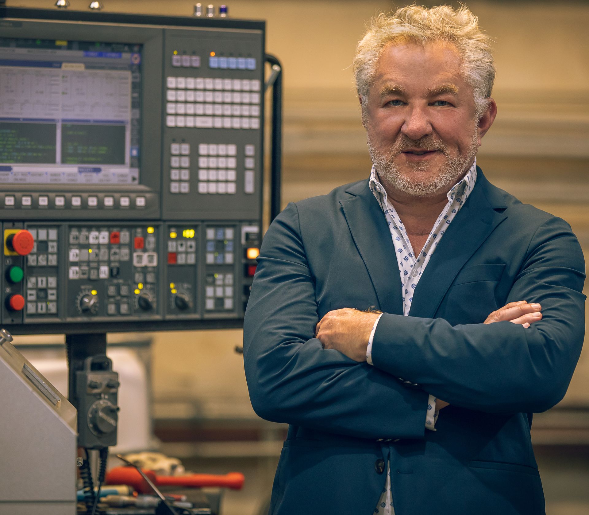A man in a suit is standing in front of a machine with his arms crossed