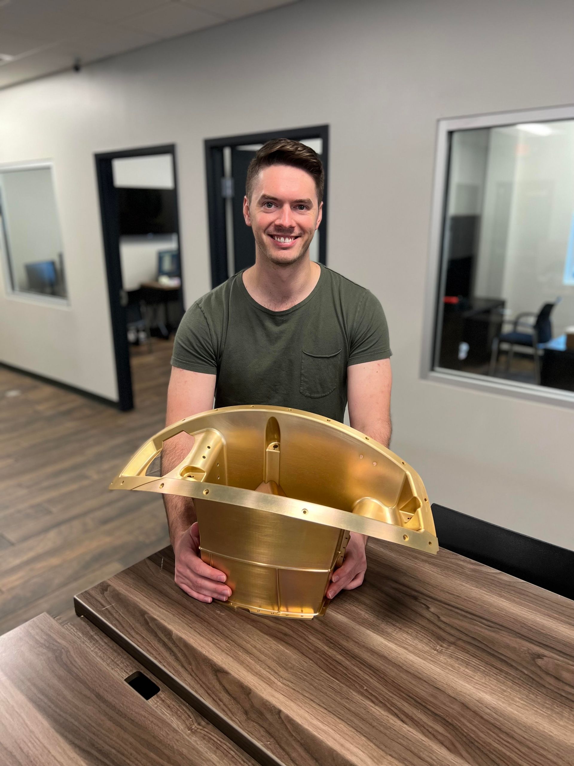 A man is holding a large piece of metal on a table.