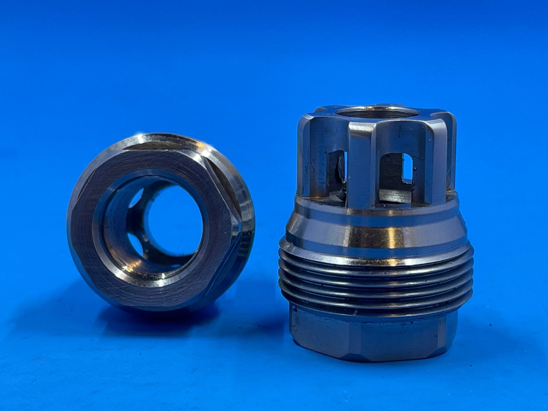 Two metal parts are sitting on a blue surface.
