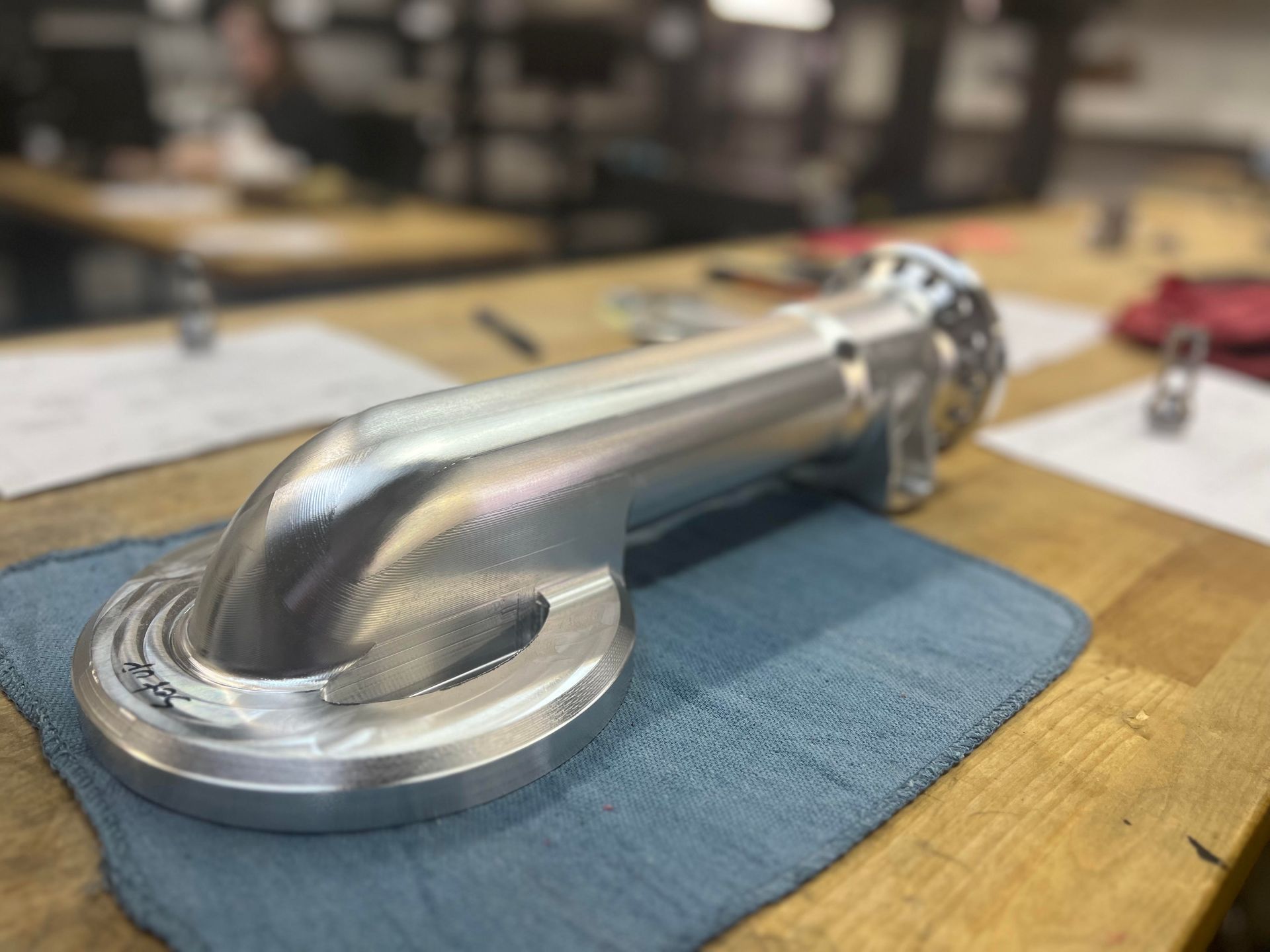 A metal pipe is sitting on a blue cloth on a wooden table.
