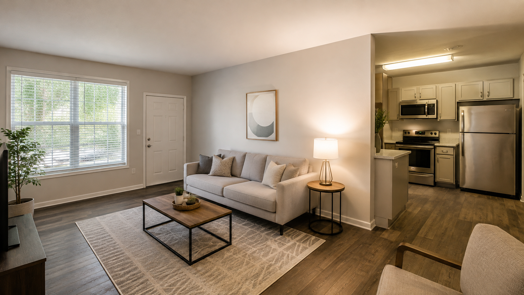 Apartment for rent with a furnished living room, large windows, and an open modern kitchen.
