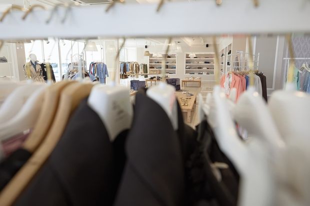 Un mucchio di vestiti sono appesi su uno scaffale in un negozio.