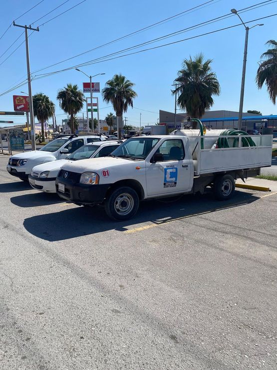 Una fila de camiones blancos están estacionados en un estacionamiento.