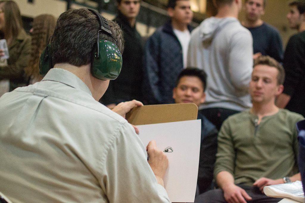 A man wearing headphones is holding a piece of paper in a comic book frame.