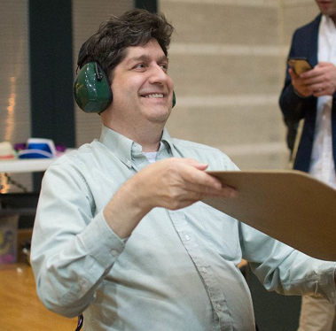 A man wearing headphones is holding a piece of paper in a comic book frame.