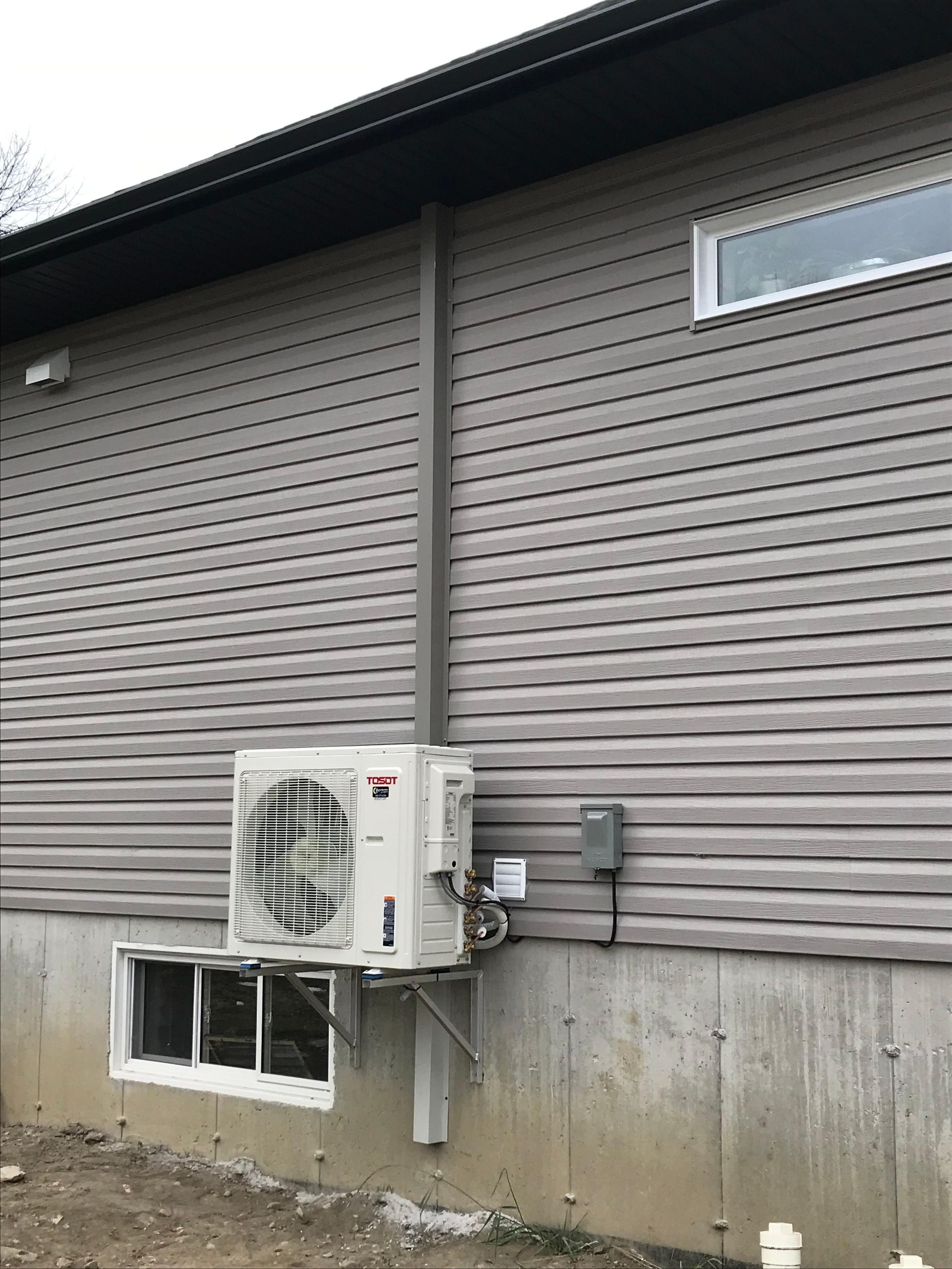 Revêtement extérieur gris avec un climatiseur et une fenêtre sur la façade du bâtiment.