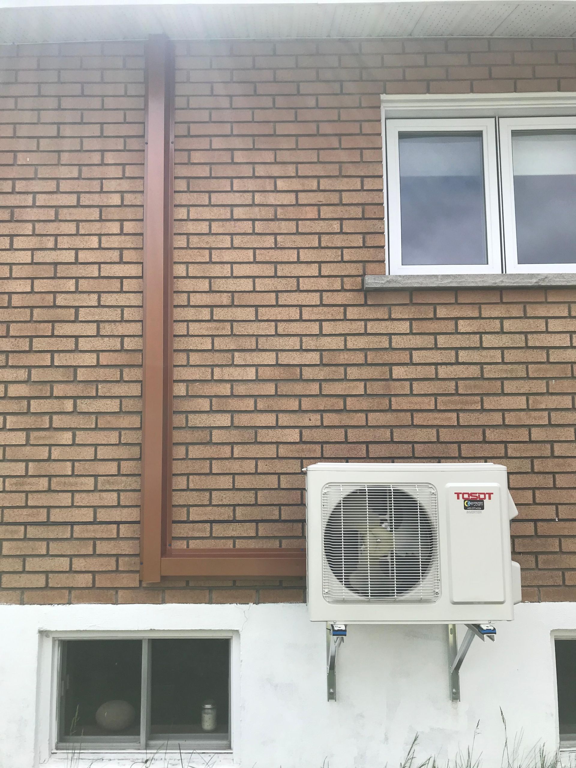 Mur extérieur en briques avec un climatiseur mural.