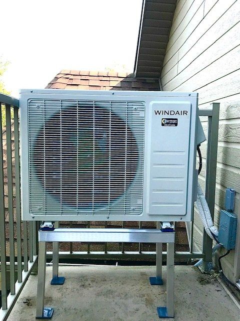 Unité de climatisation extérieure Windair sur un support métallique, installée sur un balcon.