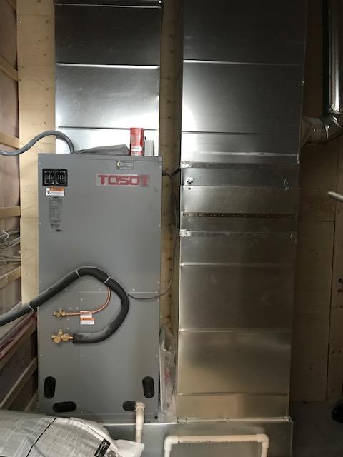 Unité de climatisation TOSO grise avec conduits installés dans un mur.